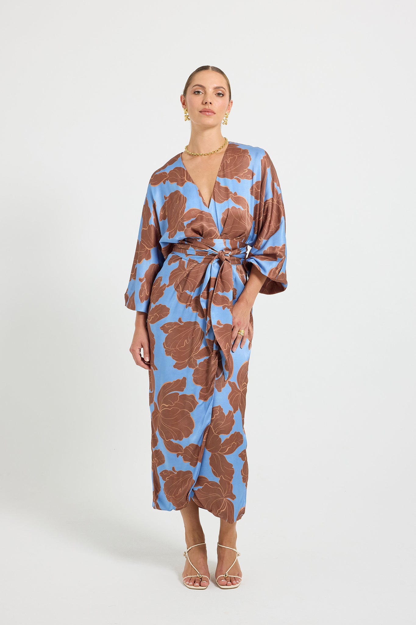 Woman wearing a blue and brown floral print wrap midi dress.