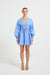 Woman wearing a light blue linen V-neckline long-sleeve mini dress.
