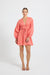 Woman wearing a coral linen V-neckline long-sleeve mini dress.