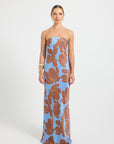 Woman wearing a strapless dress with a blue and brown floral print.