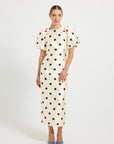 Woman wearing a Cream & Black polka dot Midi dress with short puff sleeves.