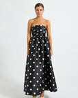 Woman wearing a black strapless midi dress with white polka dots