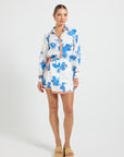 Woman wearing a white and blue floral print mini wrap skirt with tie detail and contrast binding, paired with a matching long-sleeve shirt.