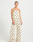 Woman wearing a cream and black polka dot top and wide-leg pants