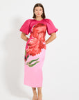 Woman wearing a pink midi dress with puff sleeves with red floral design.