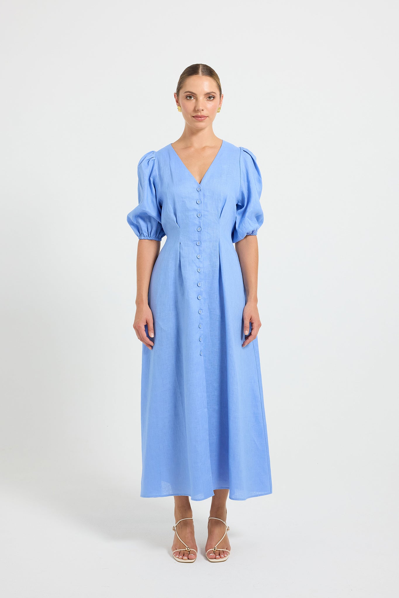Woman wearing a light blue V-neckline button-through midi dress with elbow-length puffed sleeves.