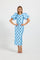 A woman modeling a light blue midi dress with black polka dots and dramatic puffed short sleeves, standing against a plain light gray studio background.