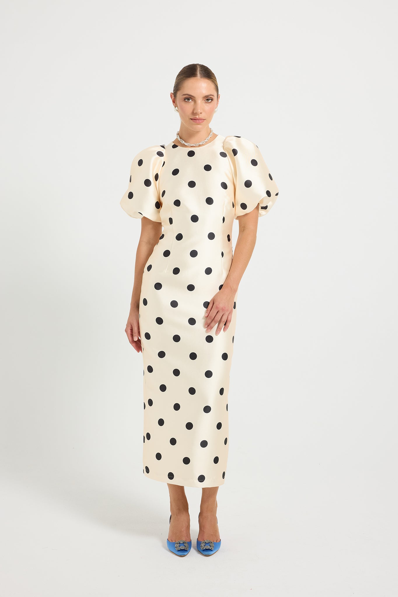Woman wearing a Cream & Black polka dot Midi dress with short puff sleeves.