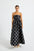 Woman wearing a black strapless midi dress with white polka dots 