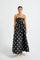Woman wearing a black strapless midi dress with white polka dots 