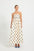 Woman wearing a strapless cream and black polka dot flared midi dress.