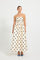 Woman wearing a strapless cream and black polka dot flared midi dress.