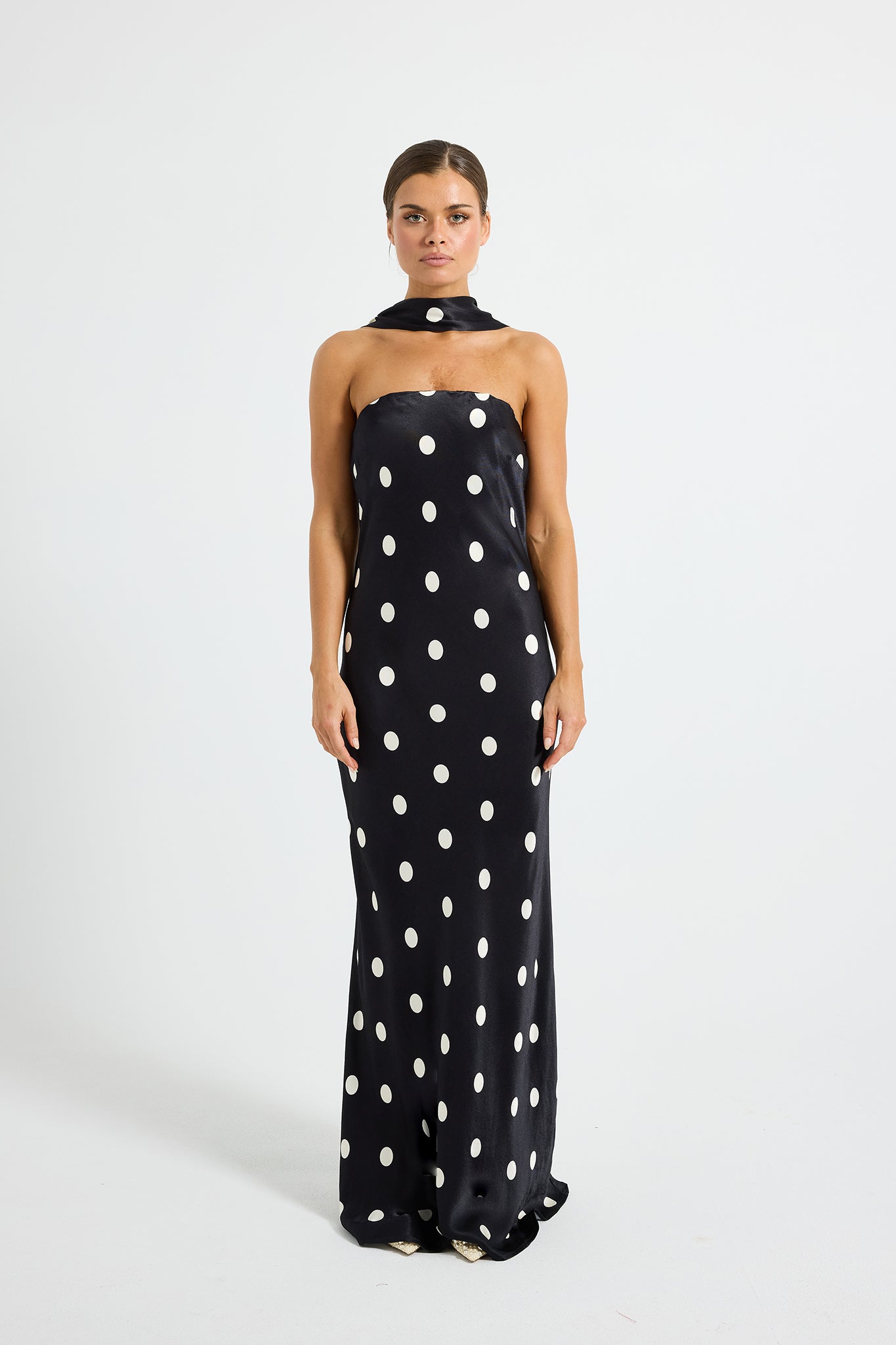 Model wearing a black and white polka dot strapless maxi dress