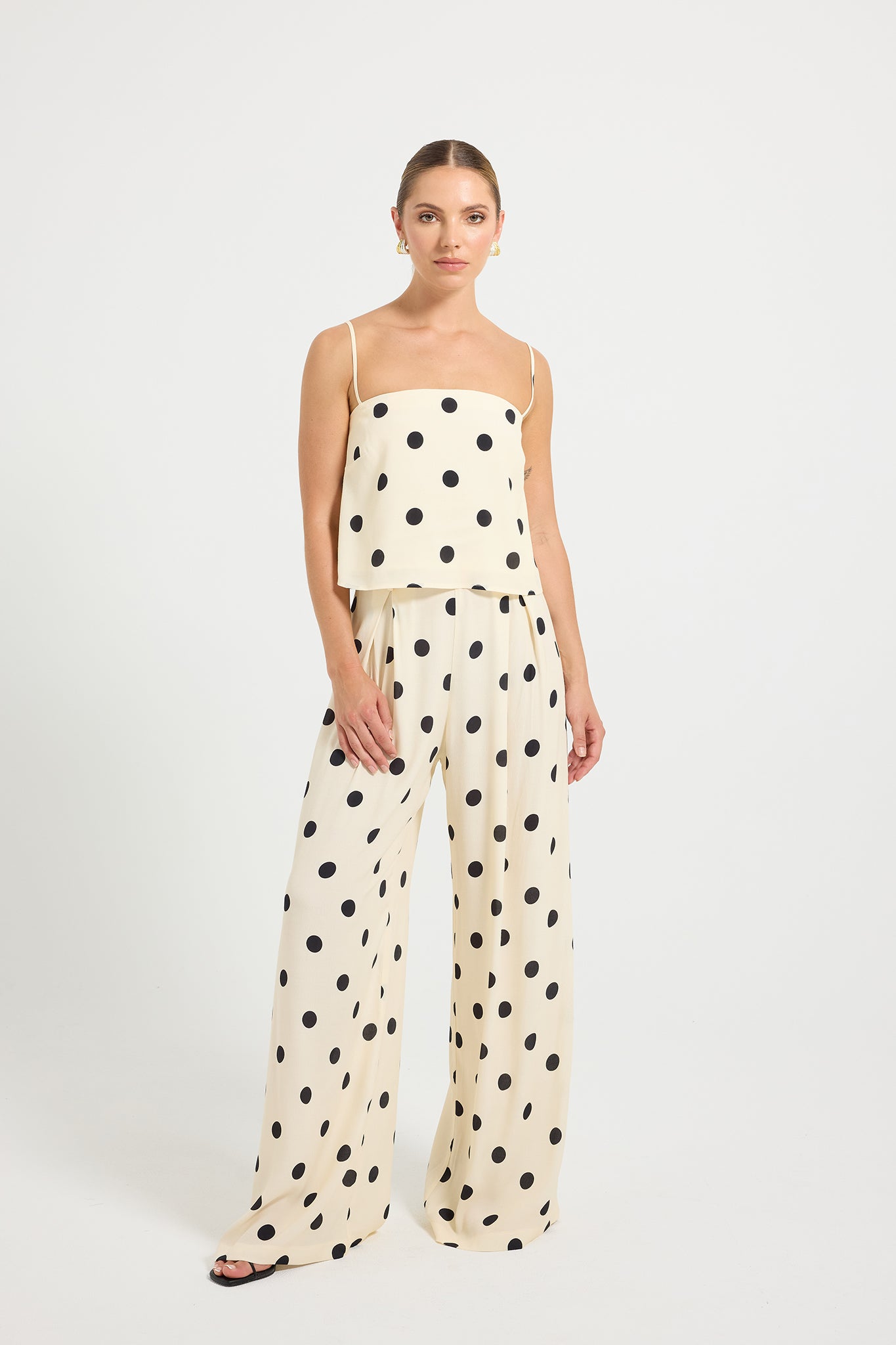 Woman wearing a cream and black polka dot top and wide-leg pants 