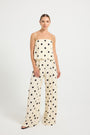 Woman wearing a cream and black polka dot top and wide-leg pants 