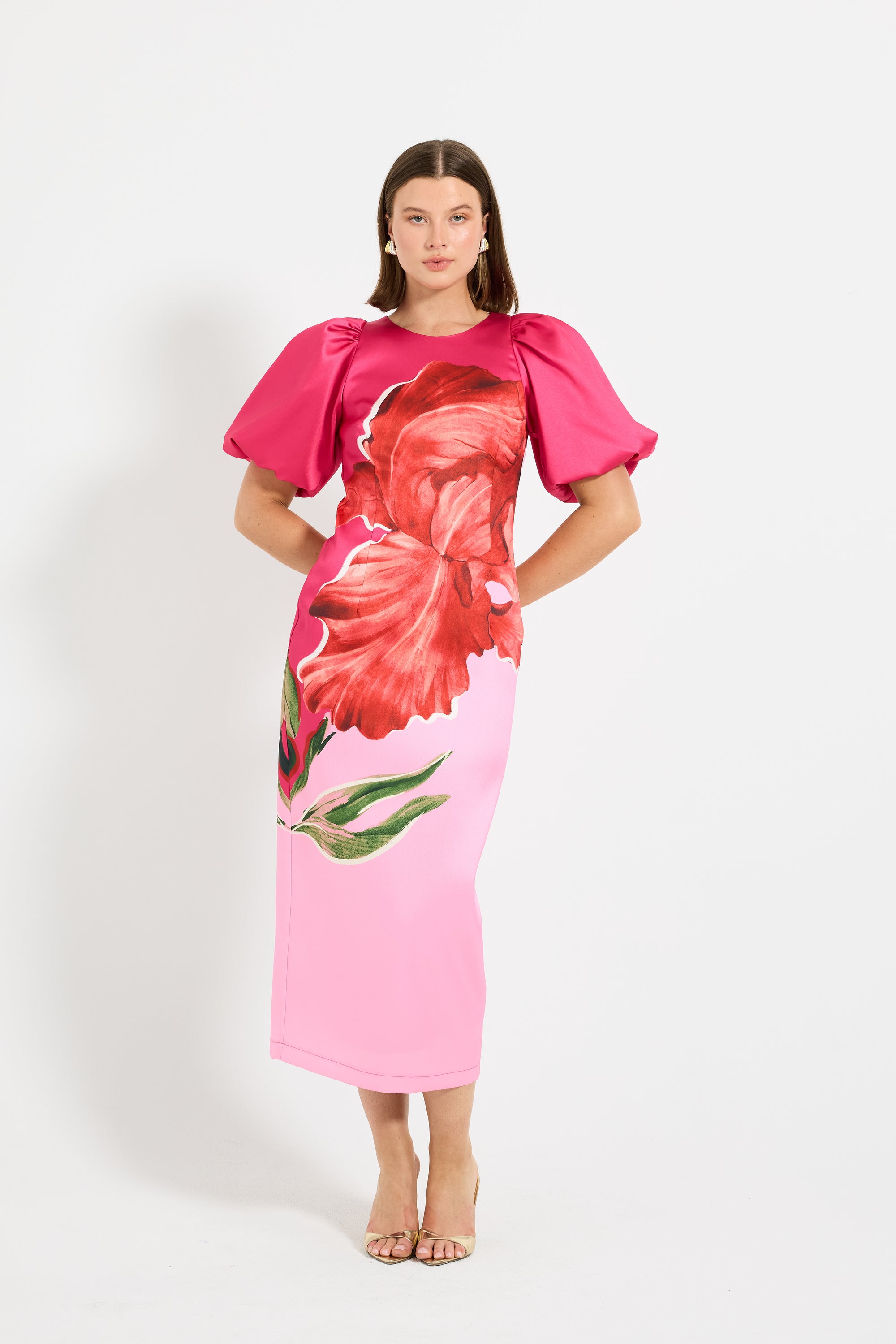 Woman wearing a pink midi dress with puff sleeves with red floral design. 