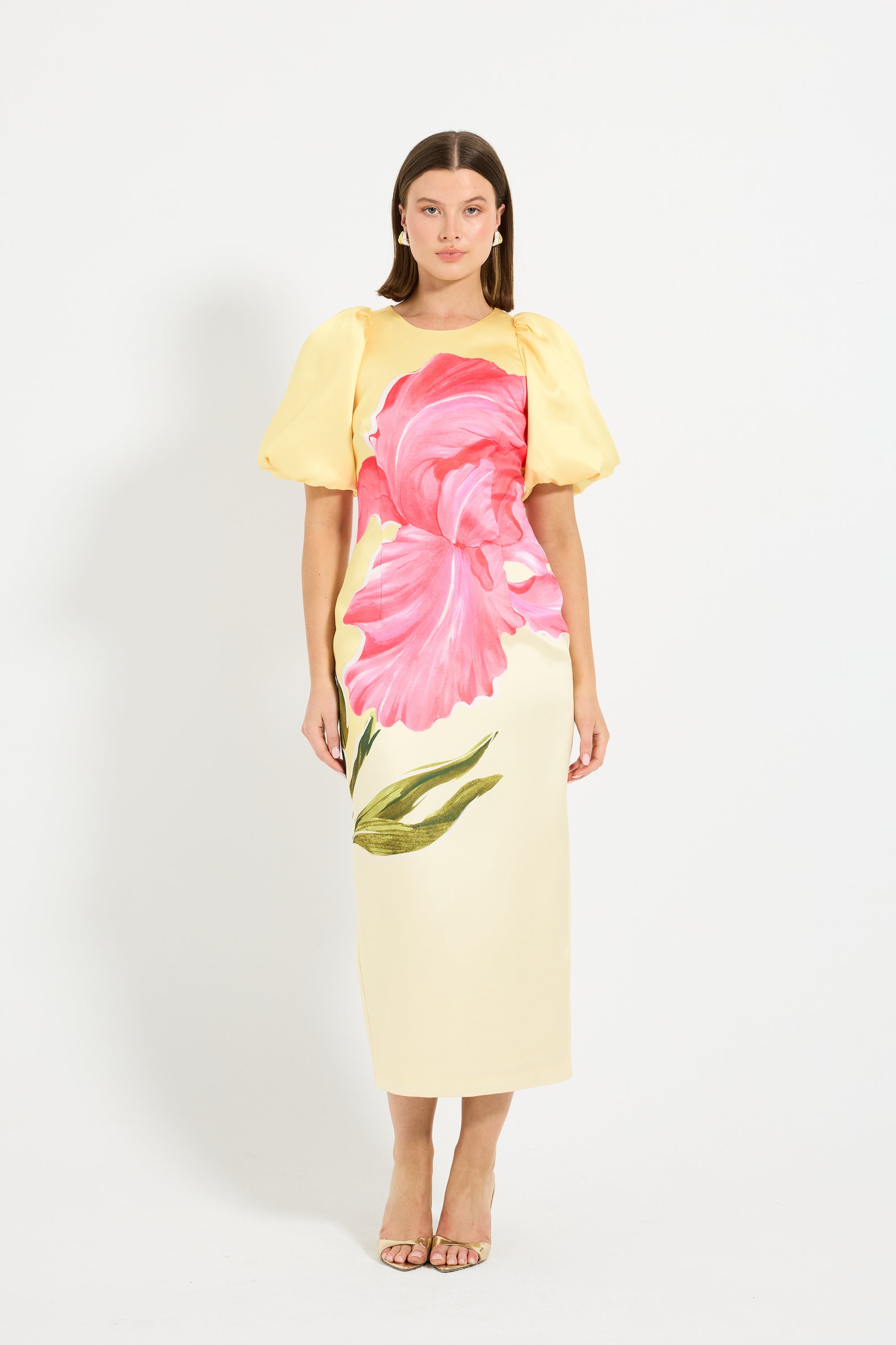Woman wearing a yellow midi dress with puff sleeves with pink floral design. 